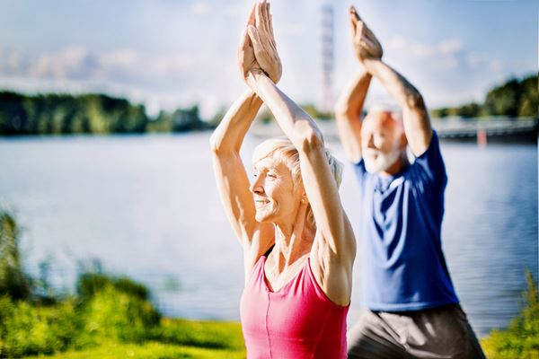 senior couple practicing yoga outdoors