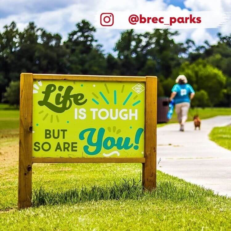 woman with dog walking on trail past sign