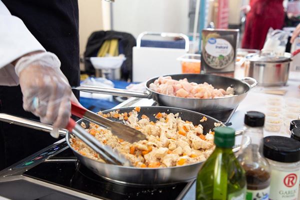 person's hand stirring pasta in a pan