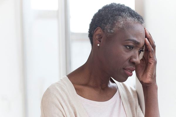 Older Black woman holding her hand to her forehead in pain