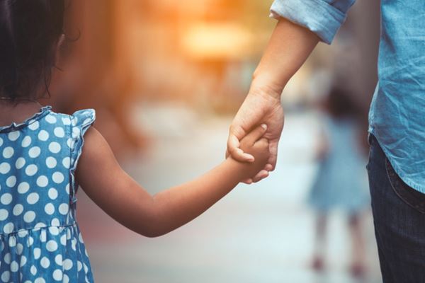young girl holding hands with adult