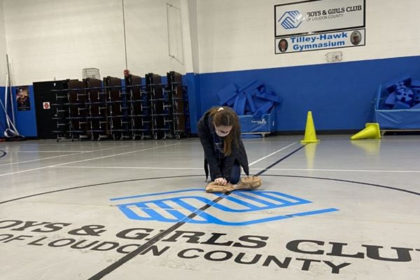 woman in gym practicing CPR on dummy