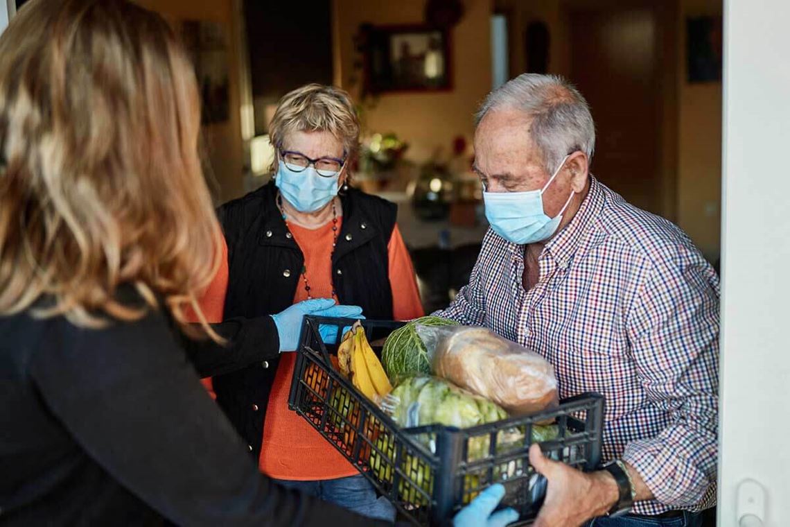 senior couple in masks receiving food box