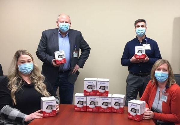 4 people hold blood pressure machines in boxes