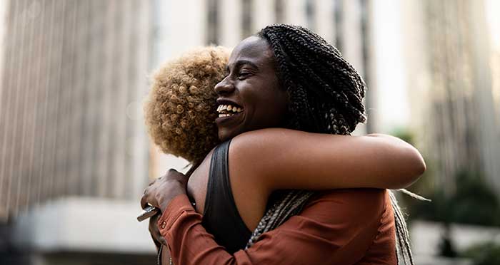 two happy women hugging in downtown setting