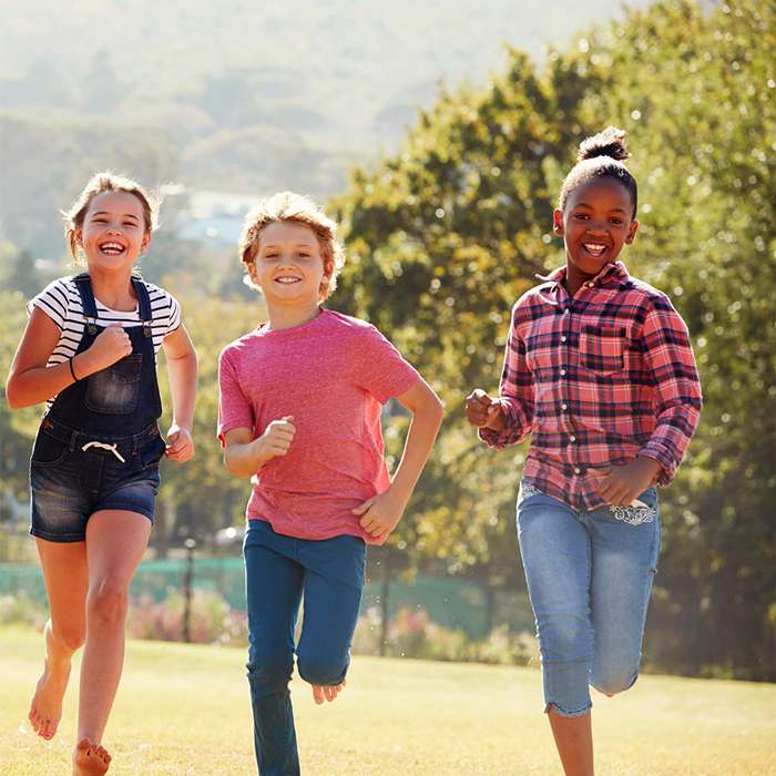 Three children in a park running toward camera