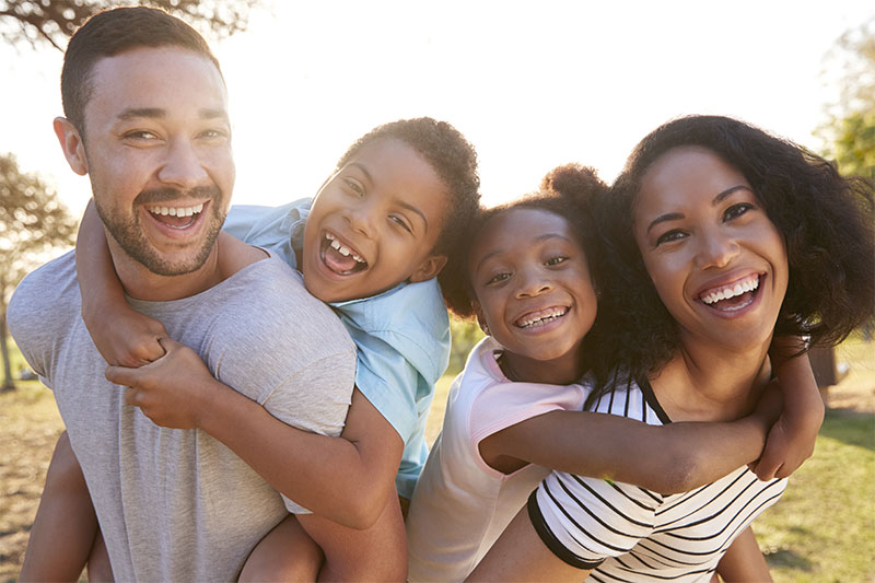 Family smiles as they enjoy walk in the park together.