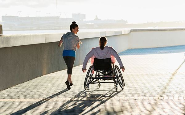 Woman in wheelchair with another woman jogging