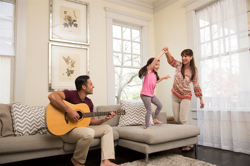 Father playing a guitar while mother and daughter dance