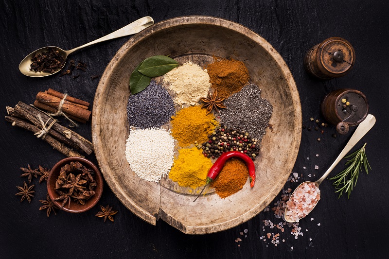 Global Cuisine vintage wooden plate full of colorful spices and ingredients