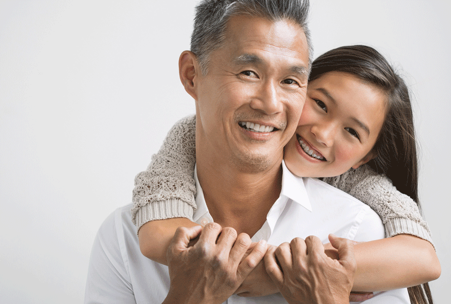Image of girl hugging father while both smile at camera