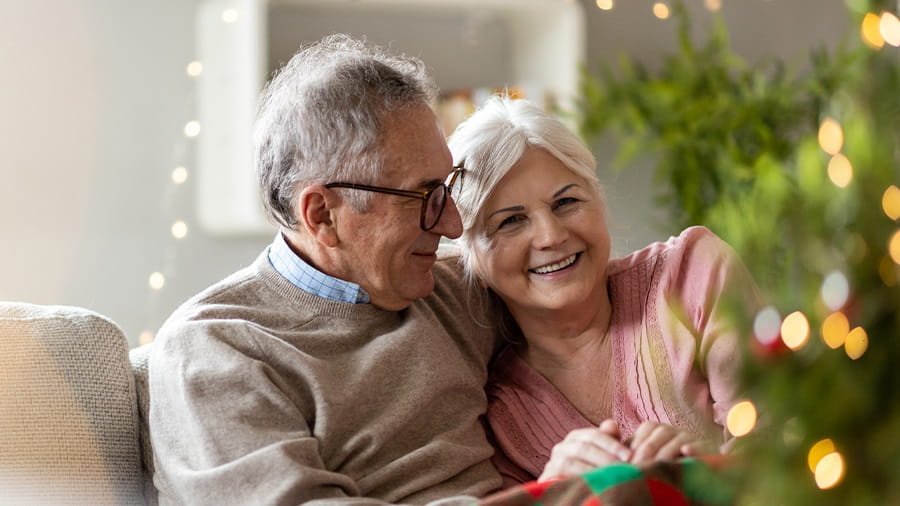 Elderly couple sitting on the couch by the Christmas tree