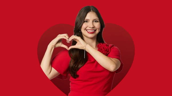 Woman holding up heart hands with a red background