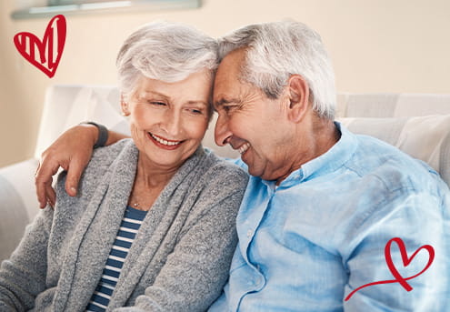 Husband and wife sitting on couch smiling