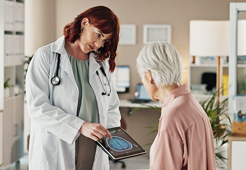 a healthcare professional showing an older woman scans on a tablet in an office