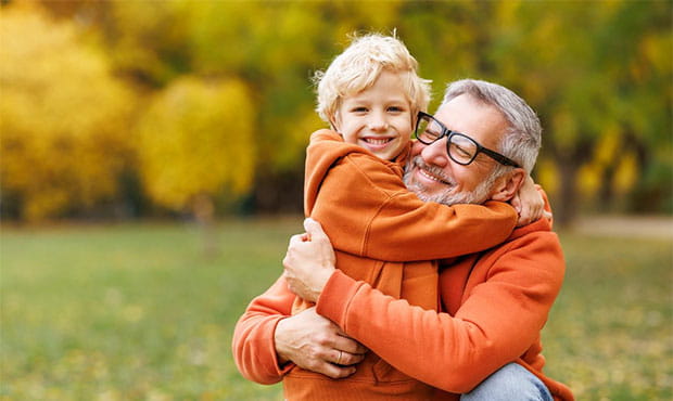 father and young sun outside in an autumn setting. they are hugging and smiling.