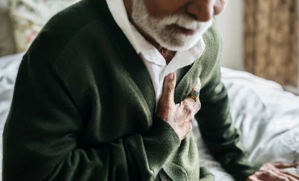 elderly man holding chest due to possible cardiac event