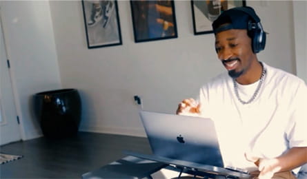 Photo of a DJ with headphones on standing at his laptop