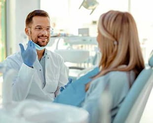 A dentist smiling at a patient in the exam room