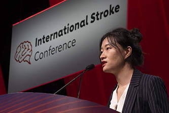 A speaker at the International Stroke Conference 2025 standing at the podium and speaking into the microphone