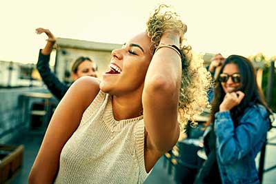 young adult friends dancing outdoors at sunset