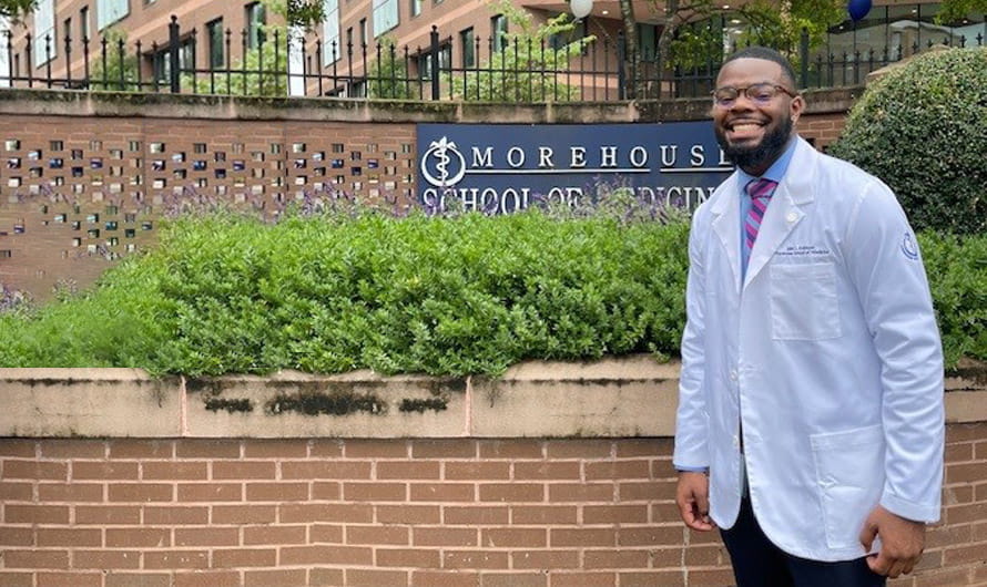 Jalen Robinson is in his lab coat standing in front of the Morehouse School of Medicine campus sign. Jalen Robinson is in his lab coat standing in front of the Morehouse School of Medicine campus sign.
