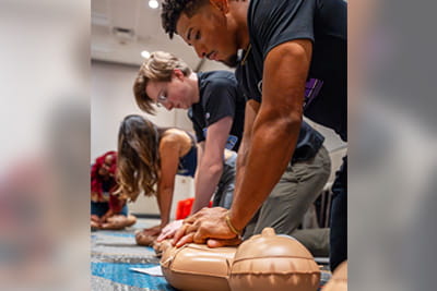 A group of American Heart Association Undergraduate Scholars are practicing CPR on manikins.