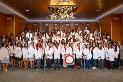 A group shot of the American Heart Association Undergraduate Scholars class of 2025-26 wearing their white coats.