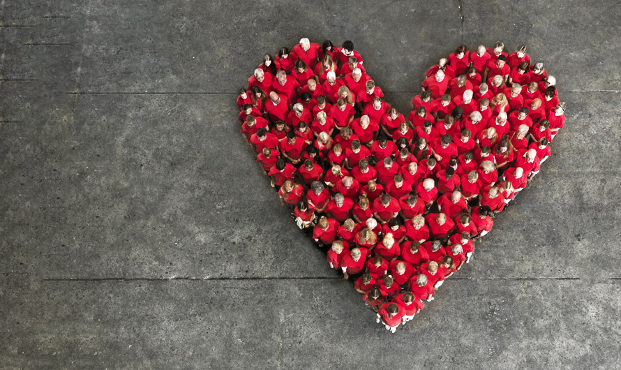 An aerial view of a crowd of people wearing red, forming a heart shape. An aerial view of a crowd of people wearing red, forming a heart shape.