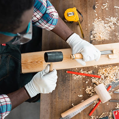 Focus on carpenter using hammer and chisel on wooden plank in workshop