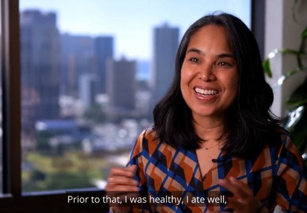 Jackie Ng Osorio smiling in a vibrant shirt with Honolulu in the backgroun