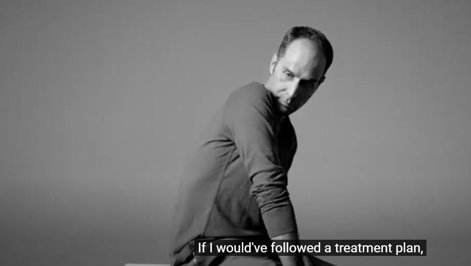 black and white image of man sitting in a chair looking over his shoulder