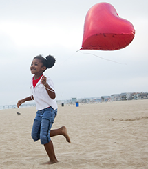 Child on the beach with a heart balloon