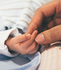 parent holding baby hand