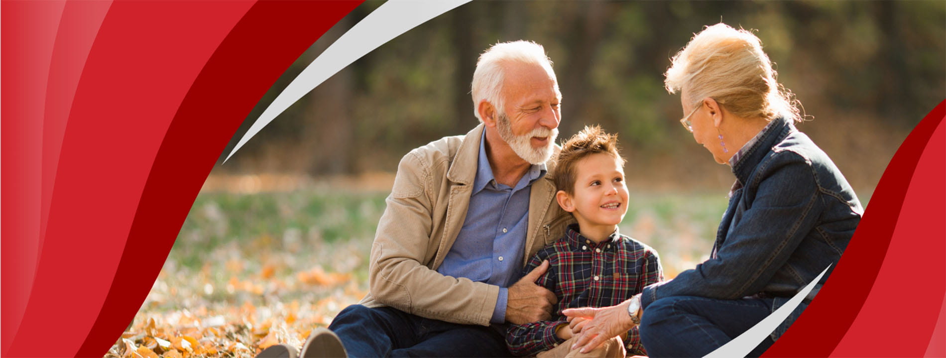 smiling grandparents sitting with their grandson outdoors