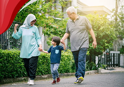 Two grandparents are walking and holding hands with their young grandchild between them