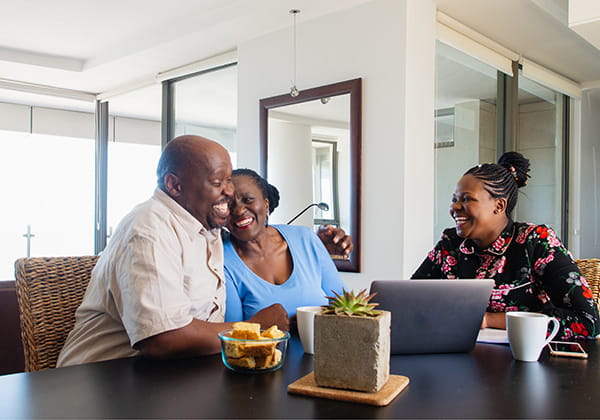 an older couple sitting at a table with an advisor, smiling and discussing plans