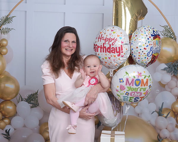 Merrie Webel holding baby Heidi surrounded by balloons