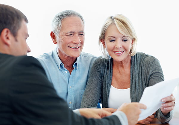 smiling older couple reviewing documents with an advisor