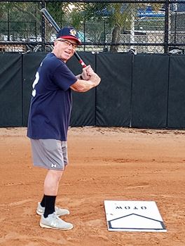 Raymond Woolsey holding a baseball bat, ready to hit a ball, standing over the home plate