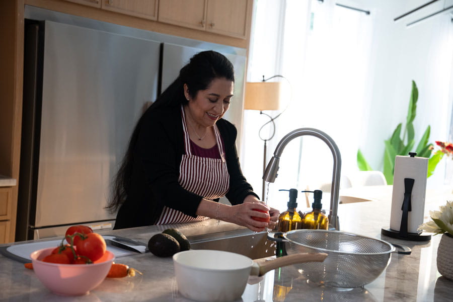 Woman washing tomatoes in her kitchen sink
