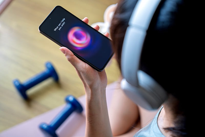 Overhead view of a woman wearing workout gear looking at her phone with an AI app open on the screen