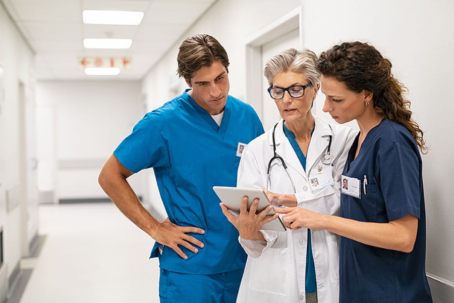 Doctor and nurses standing in a hospital hallway looking at a tablet