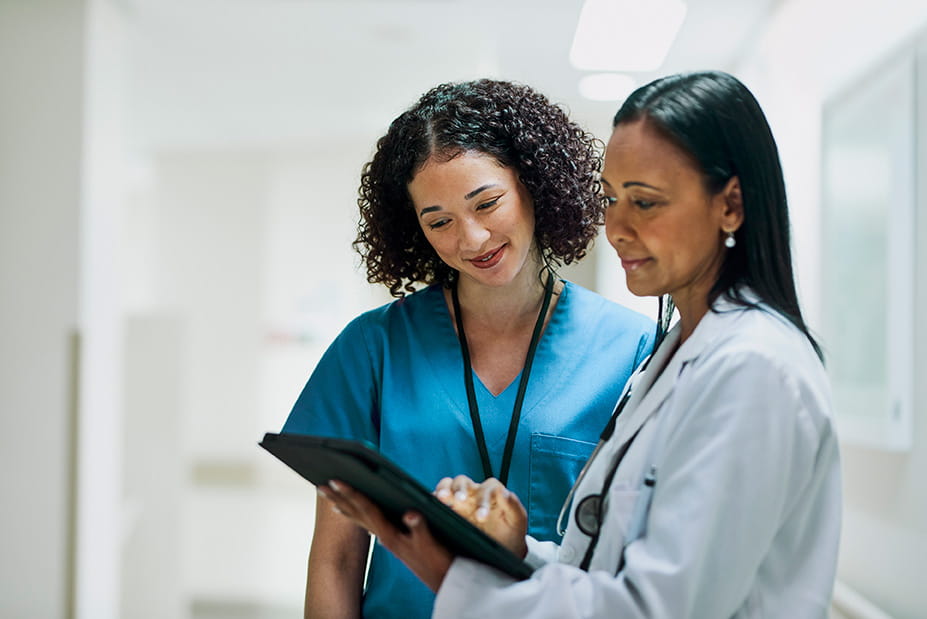Doctor and nurse with soft smiles looking at a tablet together
