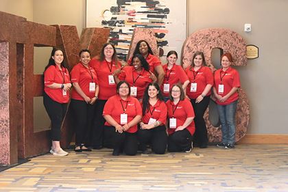 group of eleven women HeartCorps volunteers posing together in front of giant letters that spell Texas