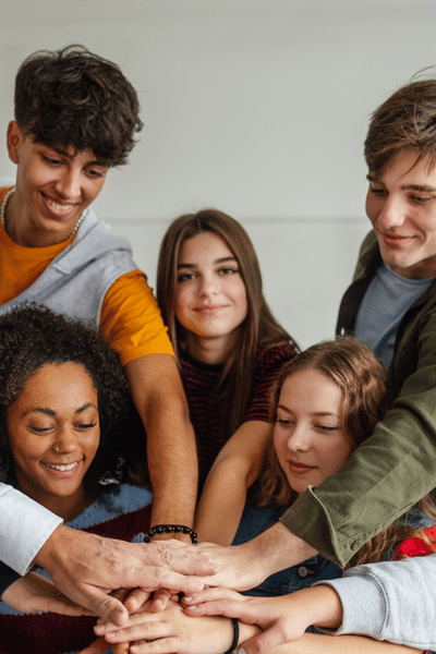 Students standing together with their hands in a pile