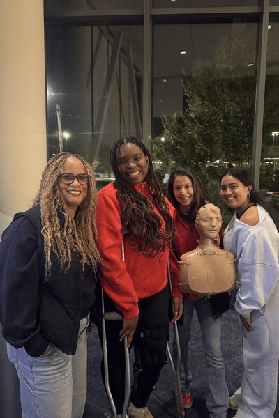 Four people holding a CPR mannequin 