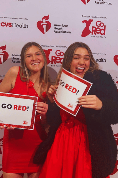 2 girls in red dresses holding "I go red!" signs
