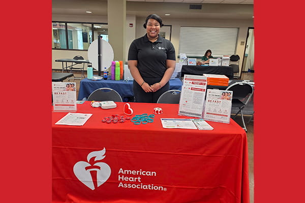 a Rural at Heart volunteer standing behind an American Heart Association table at an event