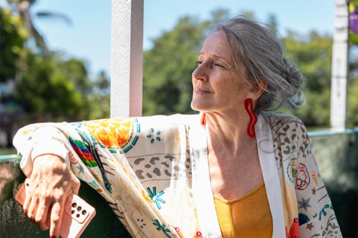 Elderly woman sitting on patio, looking off into the sunlight